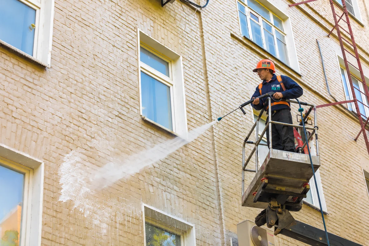 Worker pressure washing the exterior of a building